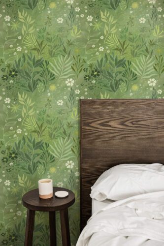 Green Whimsical Wildflowers in peel and stick wallpaper behind a wooden headboard in a bedroom.