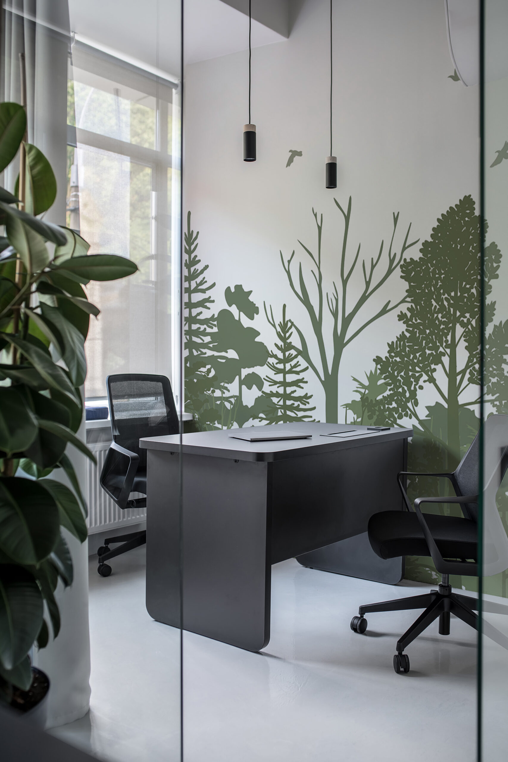 Sage Green Forest Scene non-pasted wall mural with tree silhouettes covering the full wall behind a modern office desk and chairs.