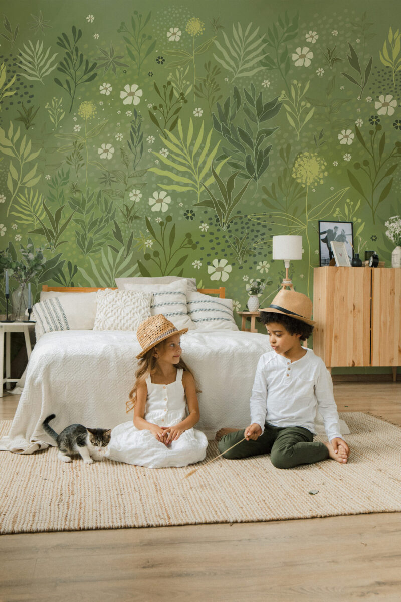 Whimsical Wild Garden peel and stick Wall Mural with layered green leaves and small white flowers covering the wall behind a bed.