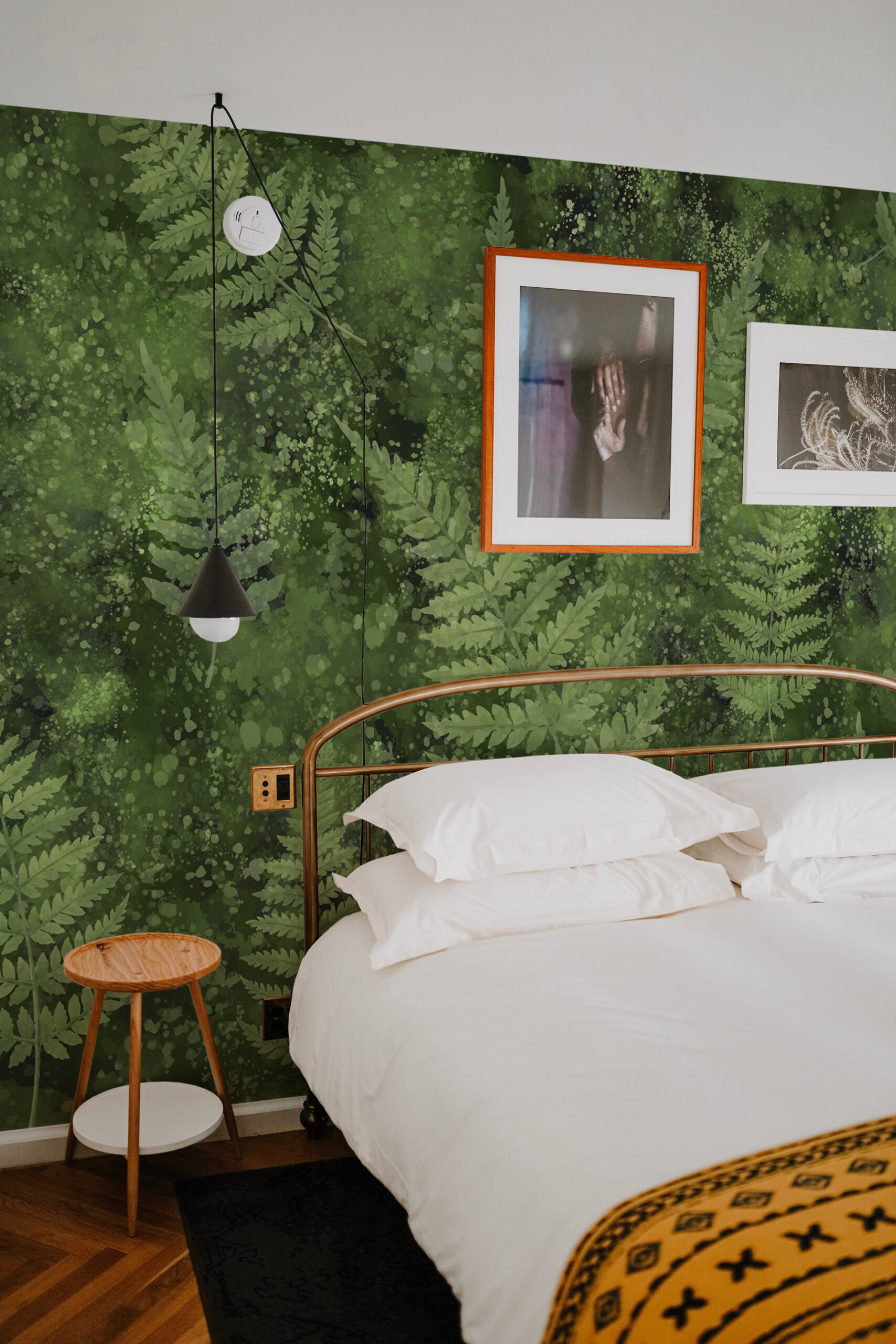 Mossy Fern Leaves non-pasted wall mural fills a bedroom accent wall in layered green fern fronds behind a brass bed frame.