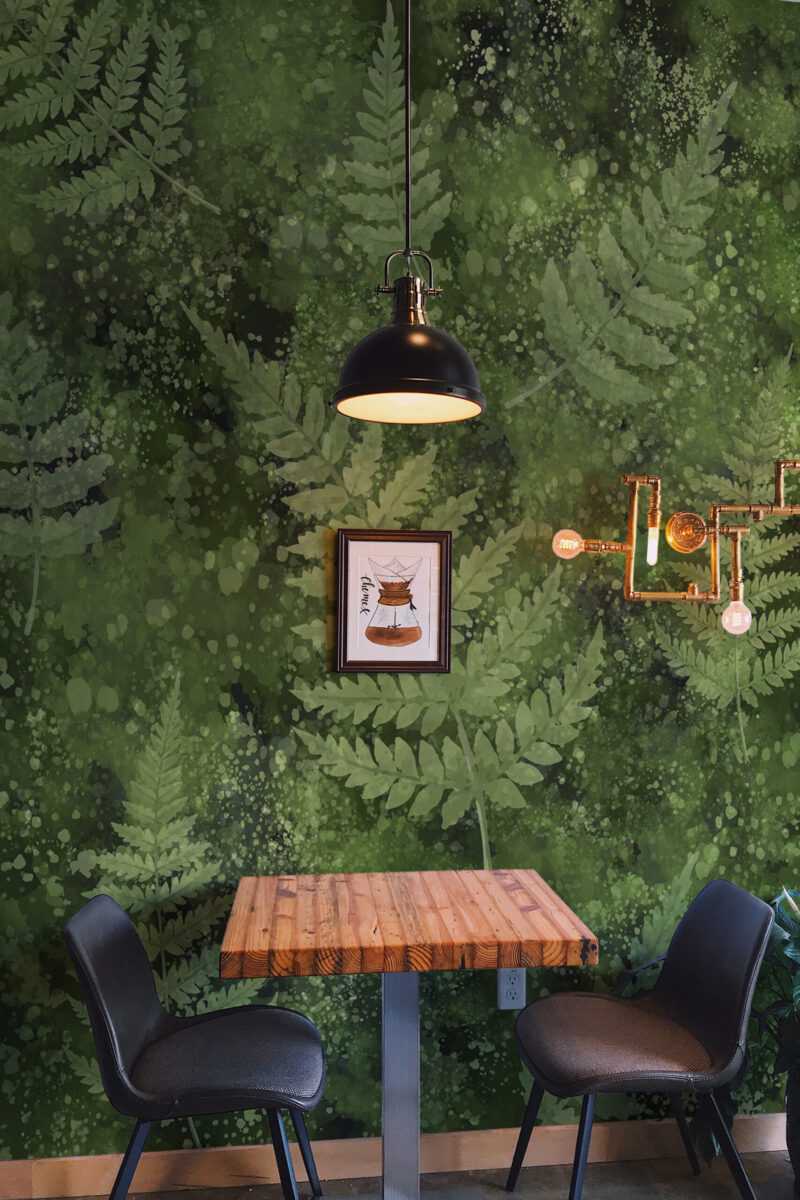 Mossy Fern Leaves peel and stick wall mural covering a cafe-style accent wall behind a small table and black chairs.