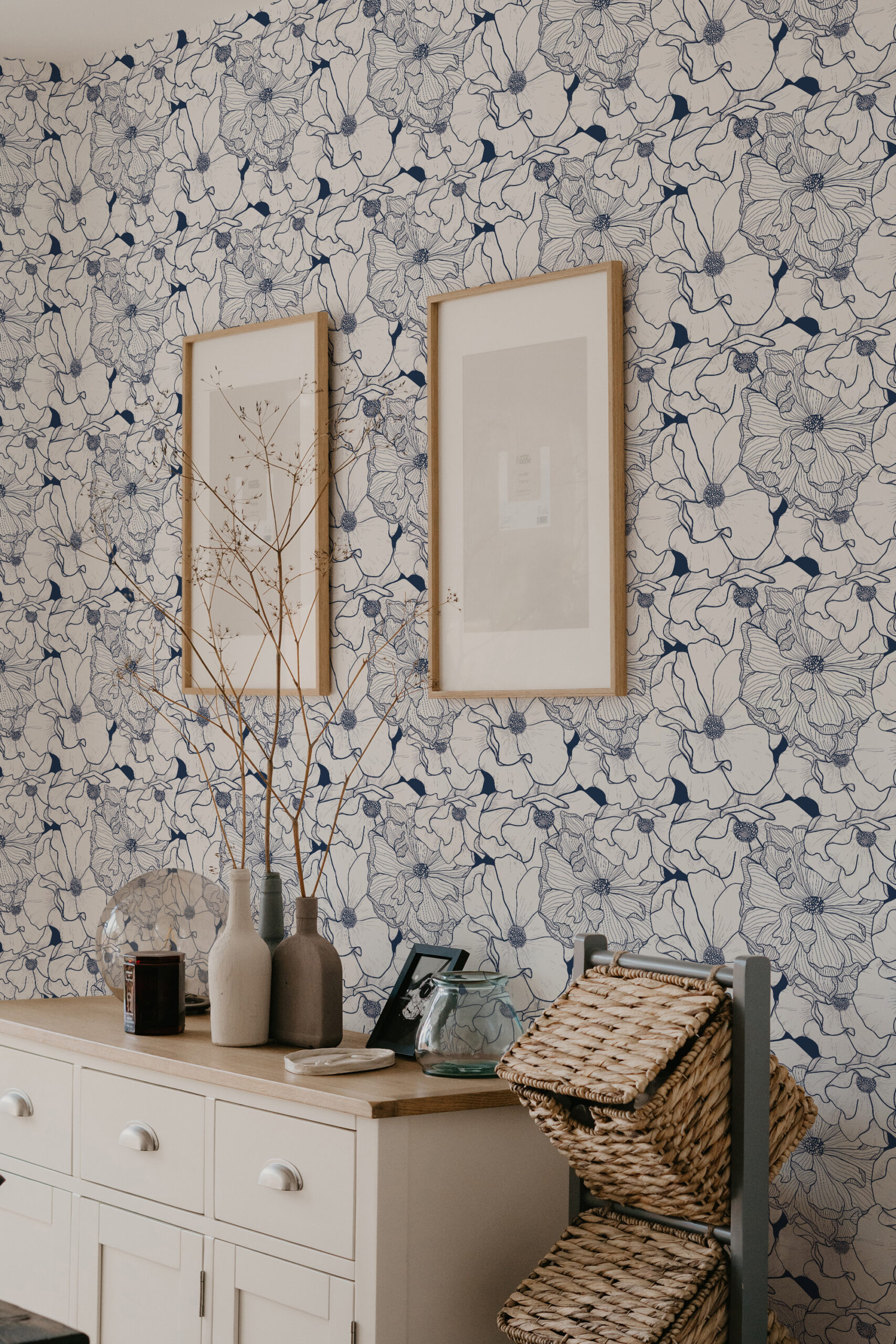 Bold Navy Flower self-adhesive wallpaper with navy line-drawn blooms on a light wall behind two framed prints.
