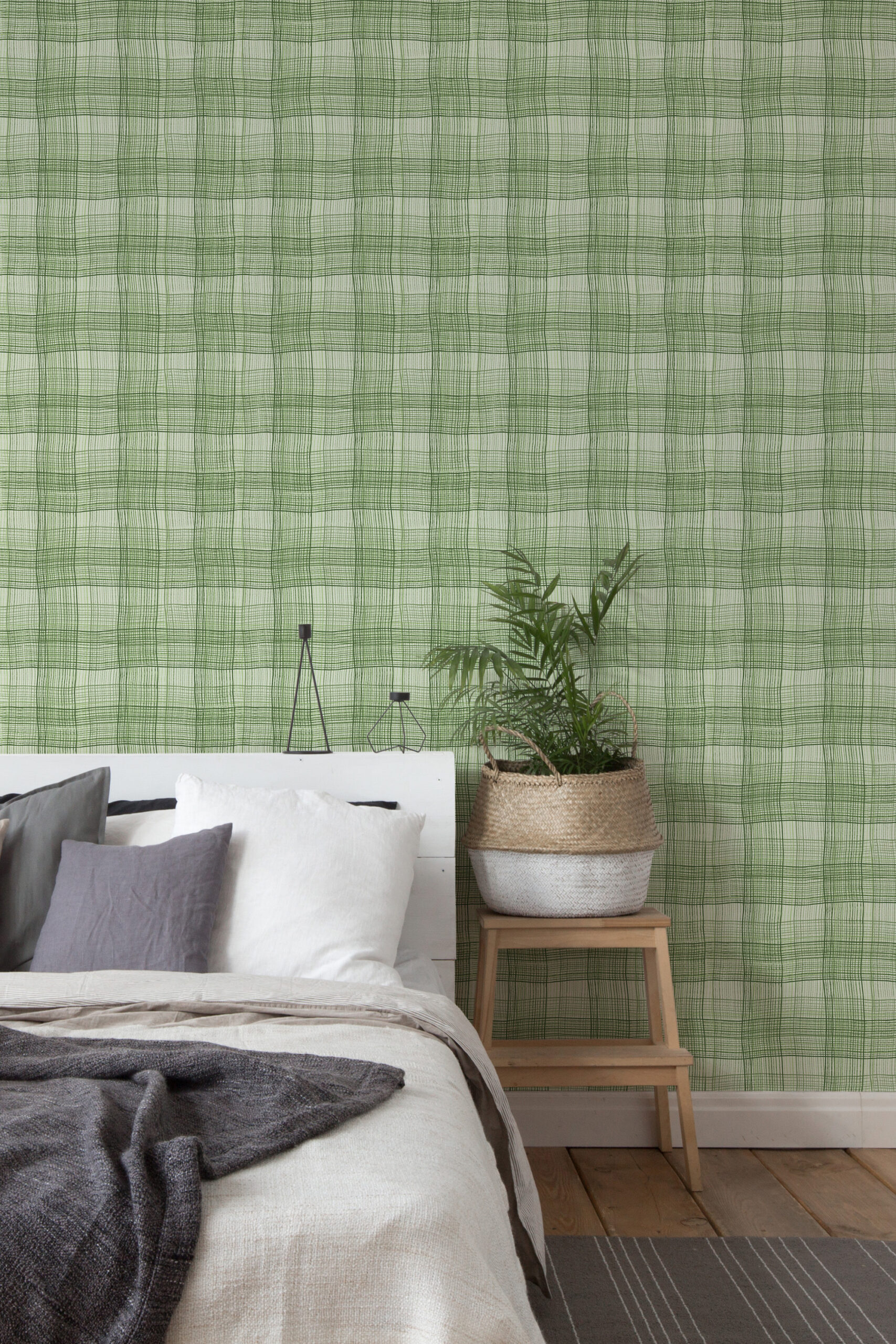 Wavy Green Plaid self-adhesive wallpaper creates a loose green grid accent wall behind a bed and a simple side table.
