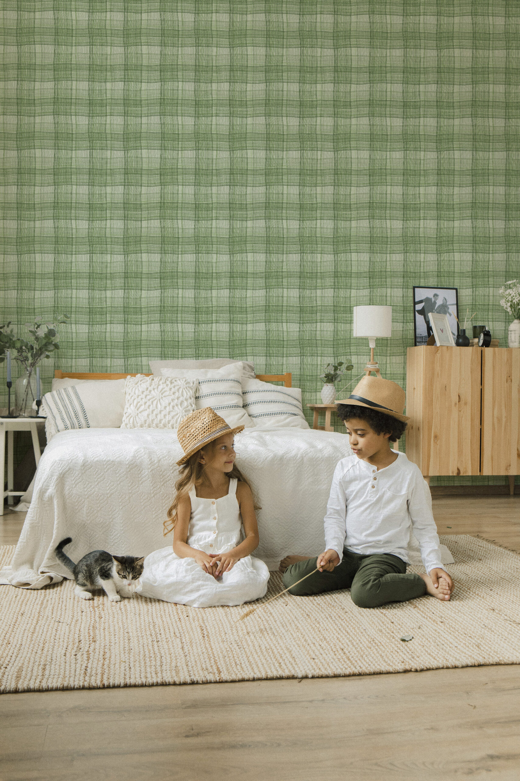 Wavy Green Plaid pre-pasted wallpaper covers a bedroom wall behind a bed, featuring a hand-drawn green plaid grid.