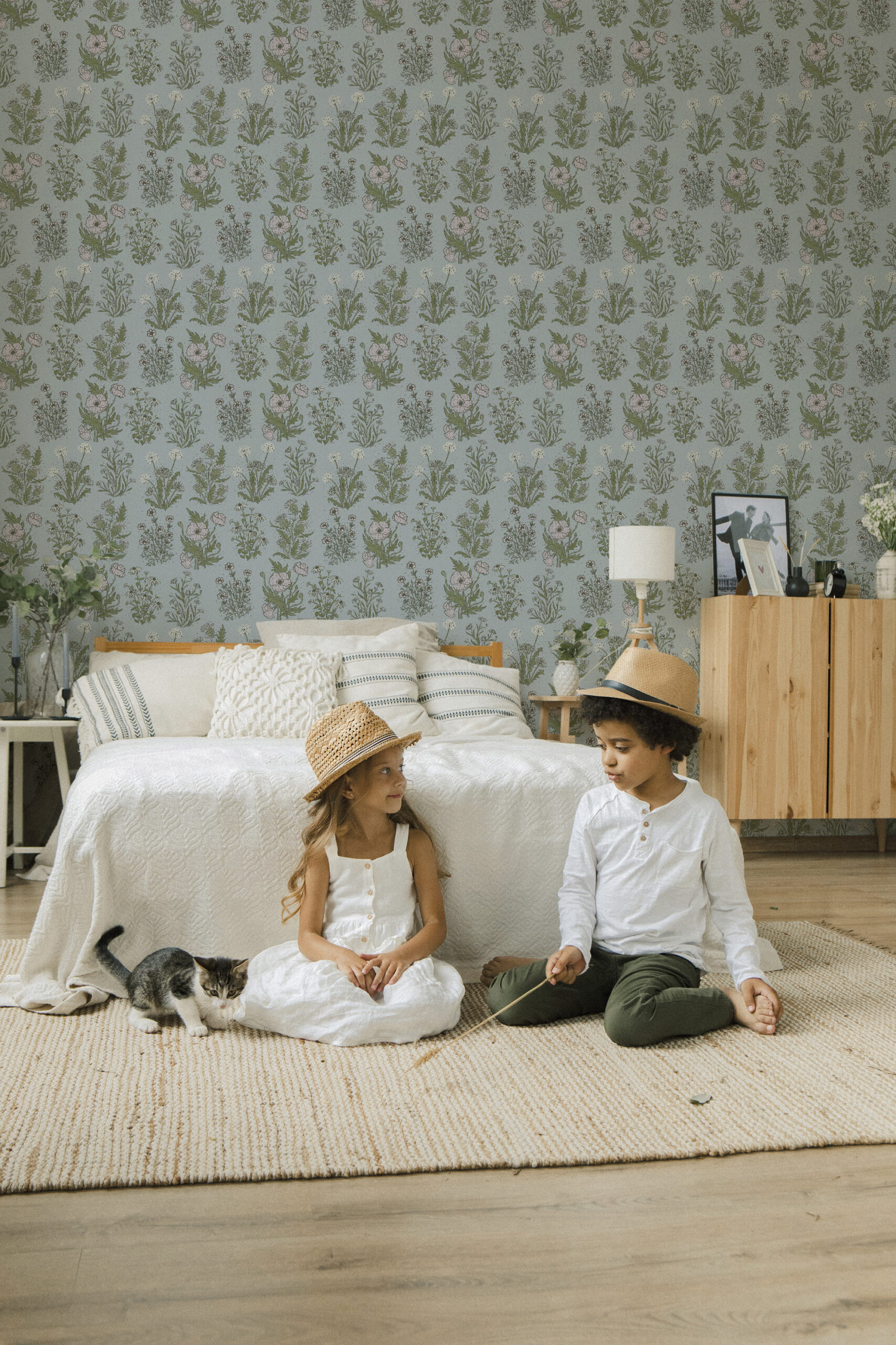 Fine Blue Wildflower peel and stick wallpaper with scattered pink blossoms and green stems across a full bedroom wall.