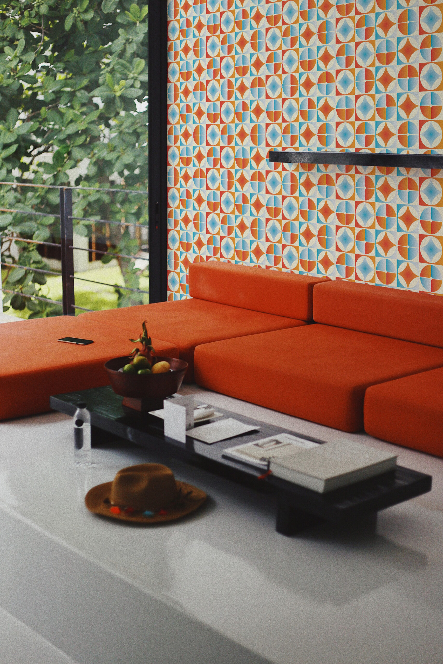 Retro Blue Orange Tile pre-pastedwallpaper with blue and orange geometric tiles covering the wall behind an orange sectional.