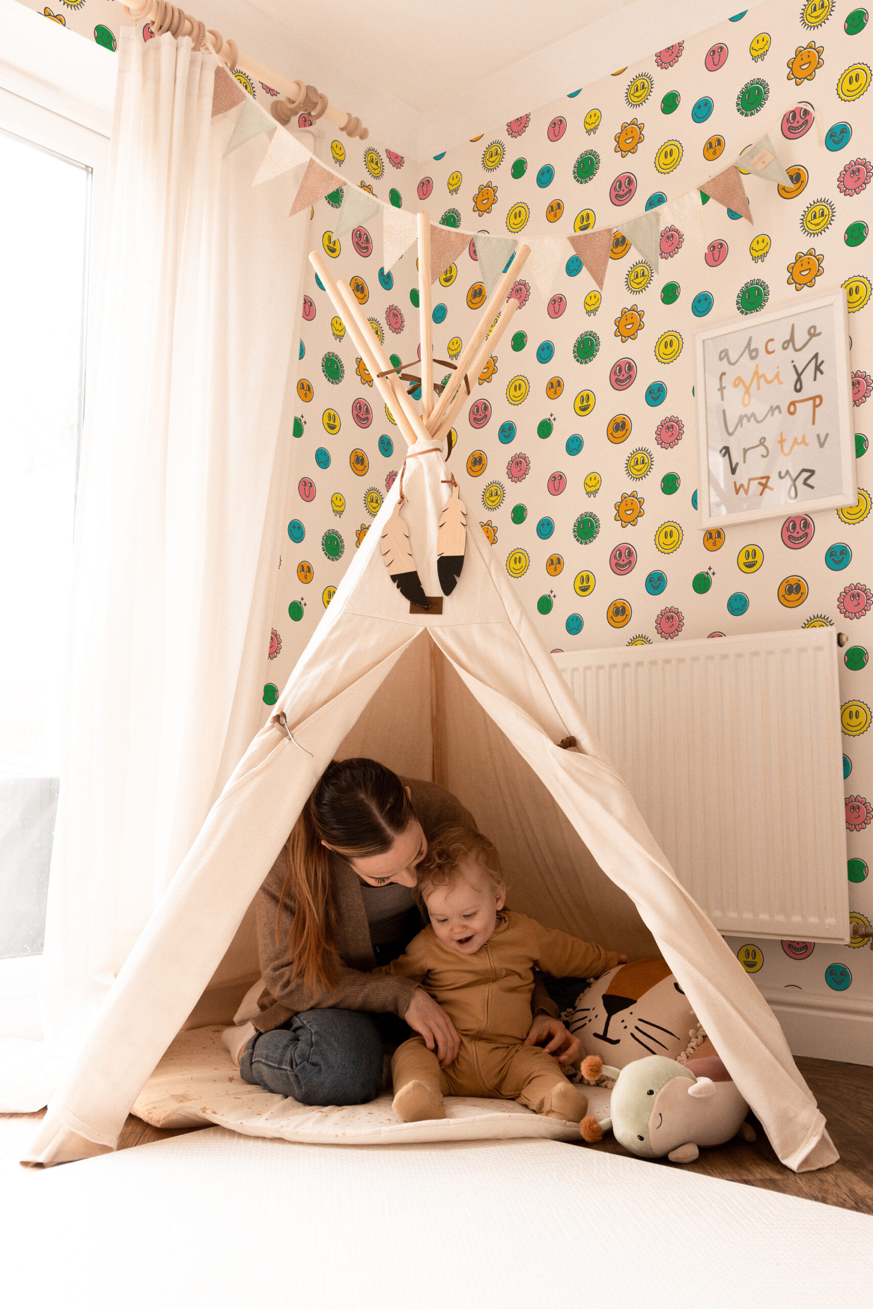 Bold Ivory Smiley pre-pasted wallpaper with colorful smiley faces and sunbursts covering a kids’ playroom wall.