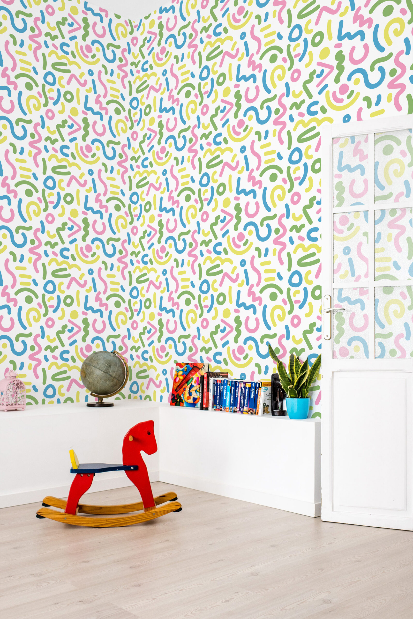 Bold White Squiggle non-pasted wallpaper in pastel pink, blue, green, and yellow covers a full wall.