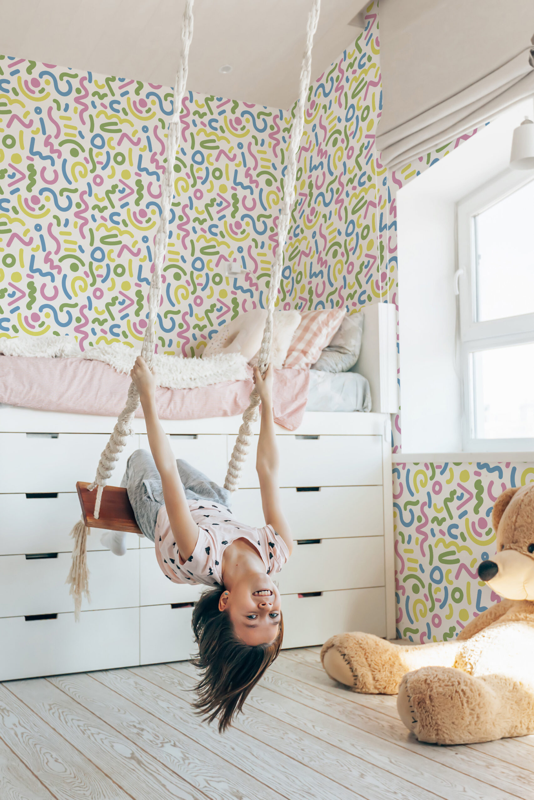 Bold White Squiggle self-adhesive wallpaper with colorful squiggles and dots across the wall in a bright kids bedroom.