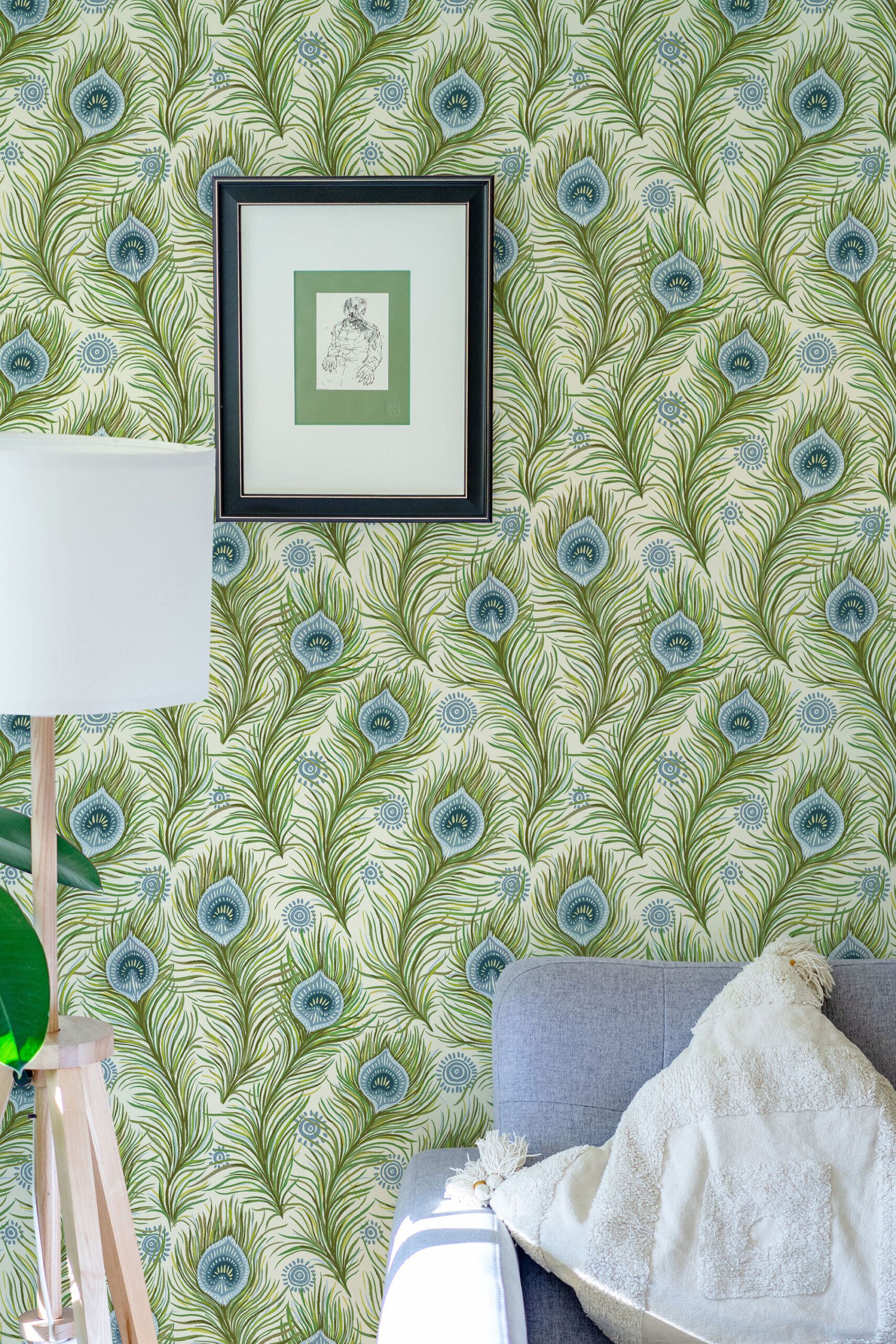 Boho Green Peacock Feather peel and stick wallpaper with green fronds and blue eye feathers behind a framed print.