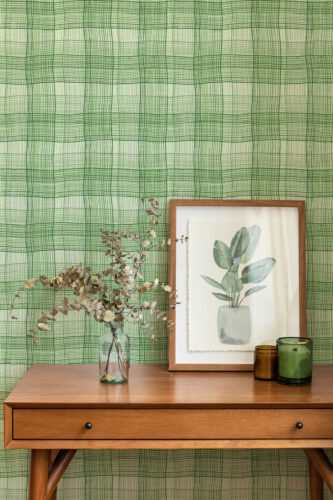 Wavy Green Plaid peel and stick wallpaper on a full wall, with a green grid pattern behind a framed botanical print.