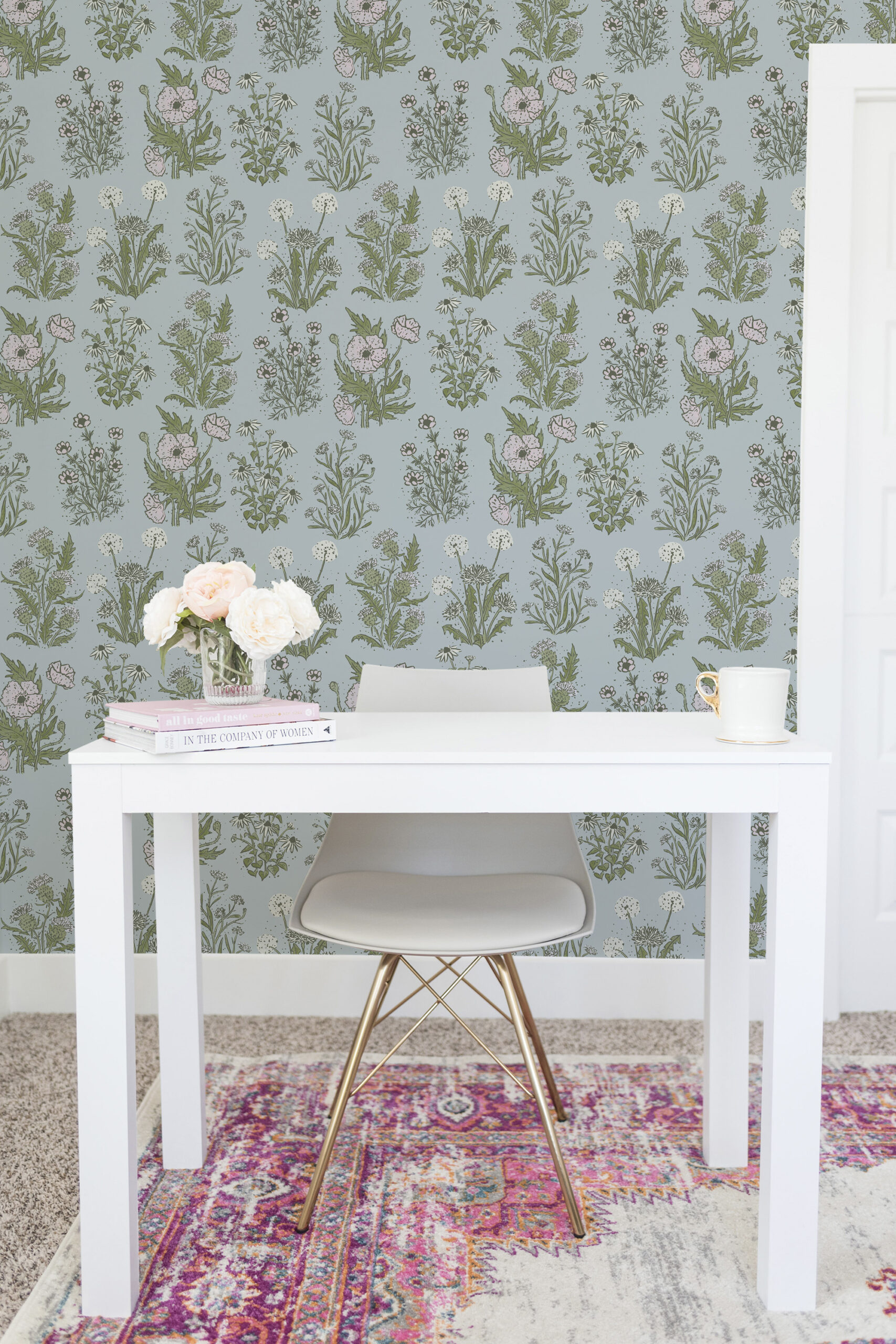 Fine Blue Wildflower peel and stick wallpaper with scattered pink blooms and green meadow stems on a soft blue wall.