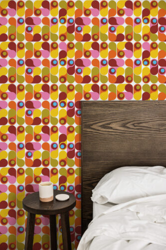 Colorful Retro Teardrop Shapes peel and stick wallpaper on a bedroom accent wall behind a dark wood headboard.
