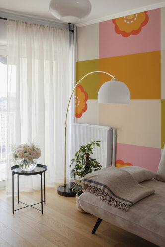 Checkered Flower Grid pre-pasted wall mural on an accent wall beside a window, with pastel blocks and orange floral shapes.