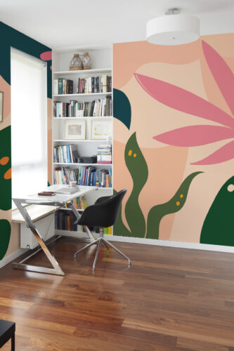 Retro Tropical Leaves non-pasted wall mural with oversized pink and green leaf shapes covering an accent wall beside a bookshelf.