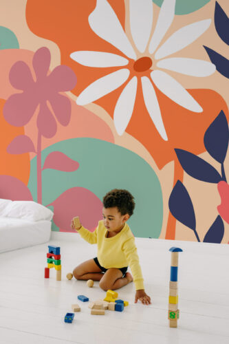 Peach Boho Floral peel and stick wall mural with oversized peach and orange flowers and navy leaves on a full accent wall in a playroom.