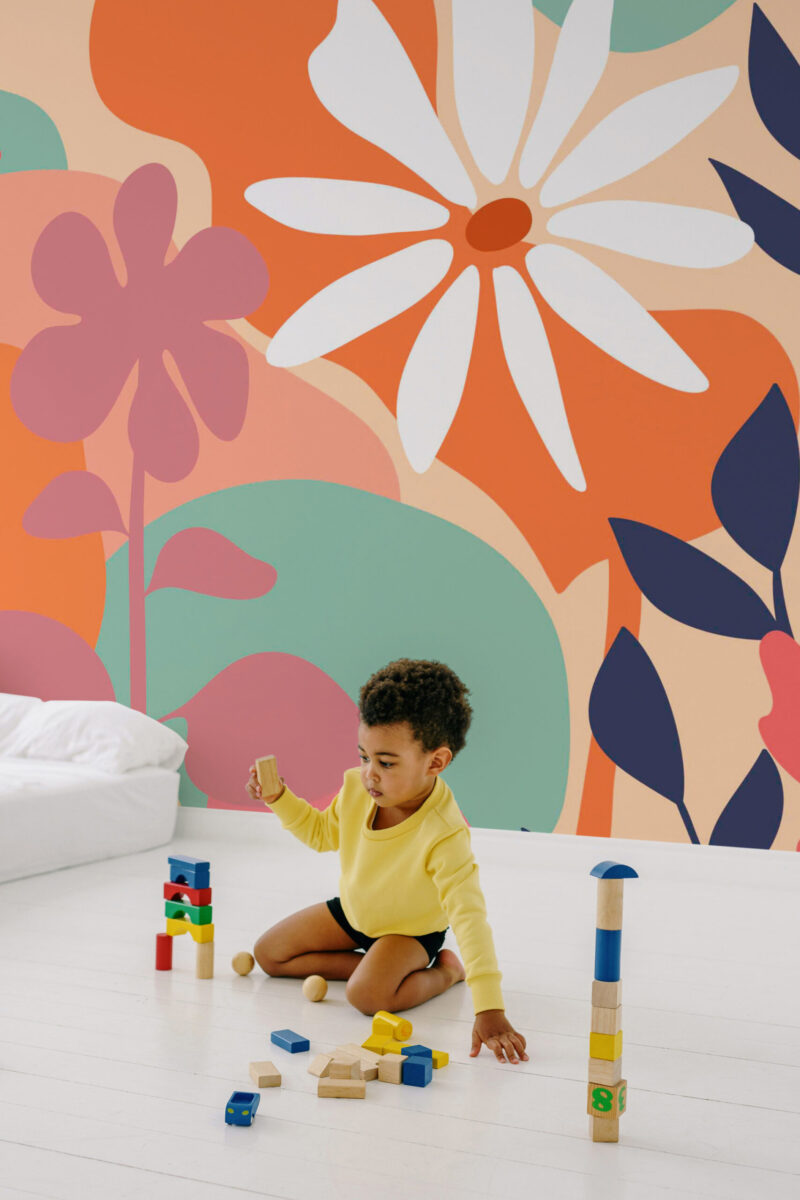 Peach Boho Floral peel and stick wall mural with oversized peach and orange flowers and navy leaves on a full accent wall in a playroom.