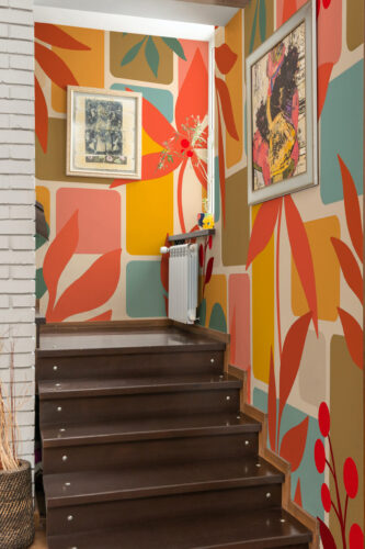 Retro Botanical Leaf Collage covers the stairwell walls as a mural, featuring bold, abstract leaf shapes in orange, teal, and pink.