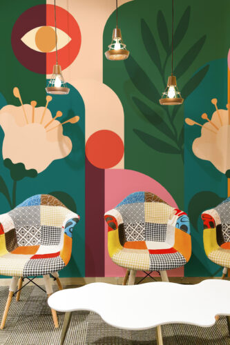 Retro Floral Garden peel and stick wall mural spans an accent wall featuring bold geometric blooms and leafy shapes in green, coral, and cream.
