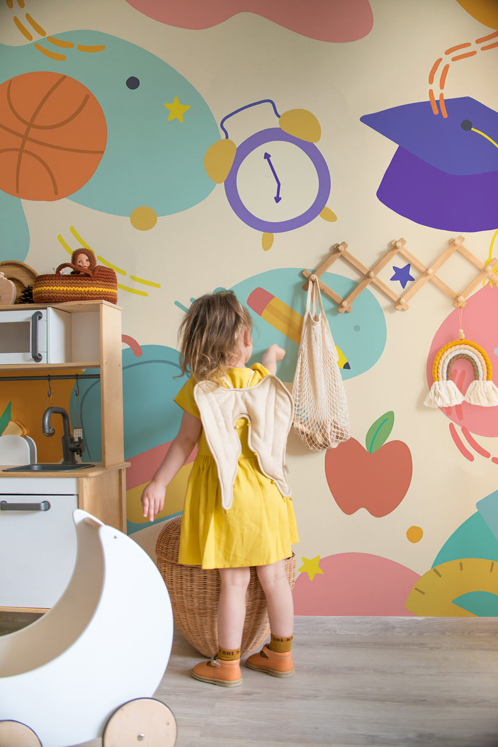 Playful School Supplies peel and stick wall mural fills a kidsยด playroom wall with bold doodles of a clock, pencil, apple, and graduation cap.