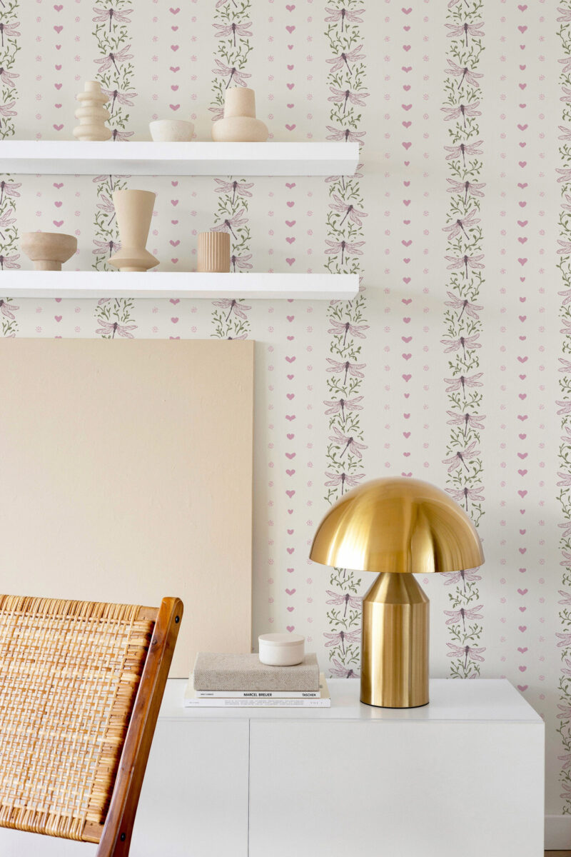 Whimsical Ivory Dragonfly non-pasted wallpaper with vertical dragonfly vines and tiny pink hearts behind a shelf and lamp.
