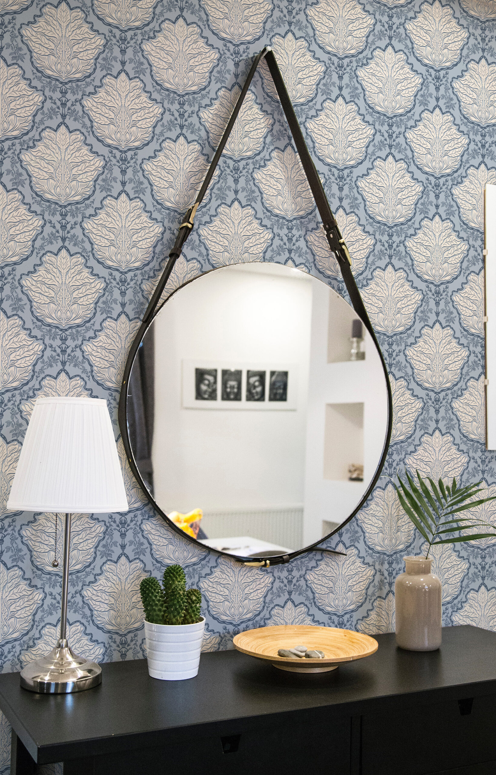 Vintage Blue Leaf Damask non-pasted wallpaper with cream leaf medallions behind a round hanging mirror.