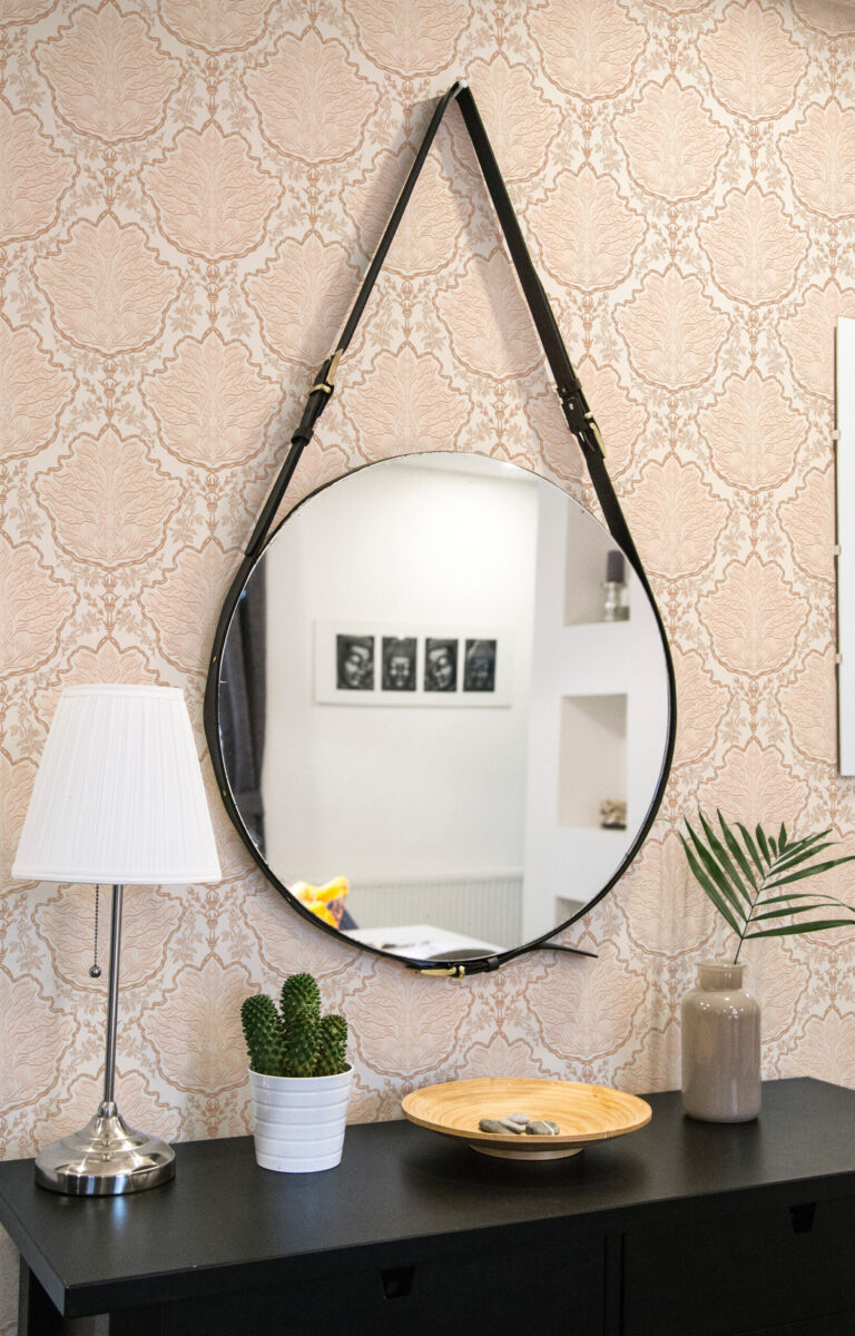 Vintage Ivory Leaf Damask peel and stick wallpaper with a soft damask leaf pattern behind a round hanging mirror.