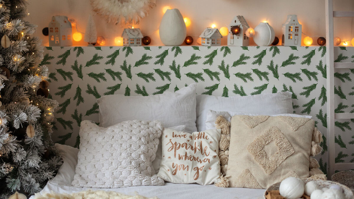 Bed with christmas pillows, decor and glowing garlands with beautiful green pines pattern wallpaper