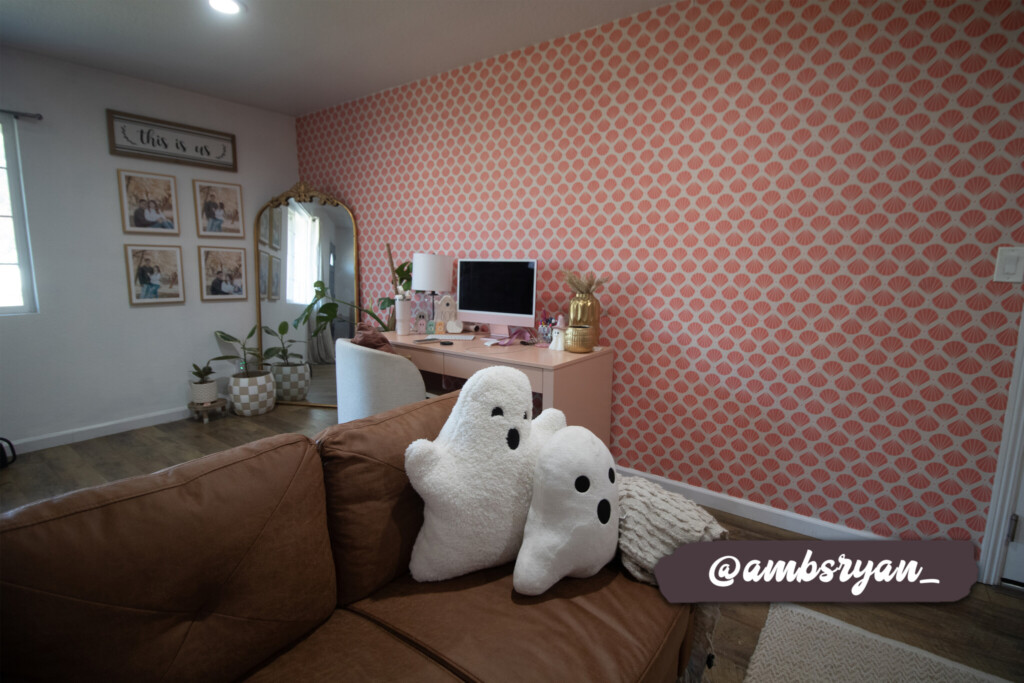 Pink fan-shaped patterned wallpaper on a feature wall, styled with a wooden shelf and decorative plants