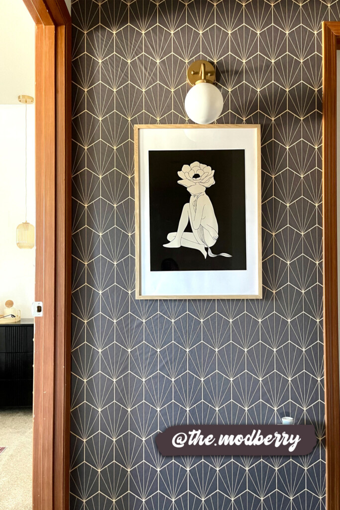 Elegant brown wallpaper with a modern gold geometric fan pattern adds sophistication and depth to a hallway, paired with framed art and a chic wall sconce