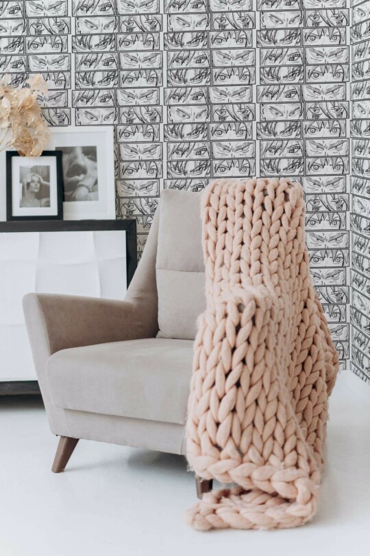 Anime abstract peel and stick wallpaper with black and white manga eyes in cozy reading nook with beige chair and chunky blanket