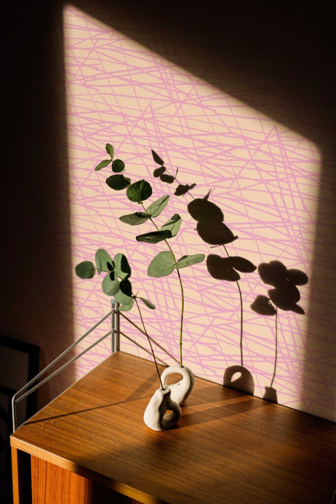 Interior with botanical shadows cast on Fancy Walls Pink Bakery Linear Vibes wallpaper. The playful pink line art over peach adds warmth and creativity to eclectic décor styles. Available in peel and stick or non-pasted materials.