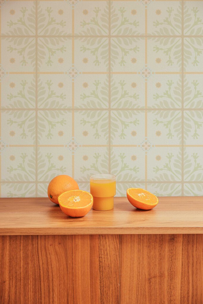 Bright kitchen countertop with oranges placed in front of a beige tile wallpaper with light botanical designs. The warm colors and clean grid layout enhance organic interiors, blending well with both modern and natural wooden elements in wellness or food prep spaces.