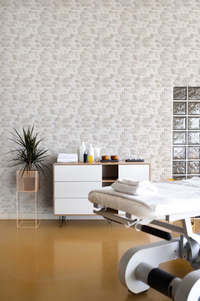 A clean beauty treatment room showcasing Fancy Walls peel and stick or non-pasted wallpaper with gray and taupe brush strokes, perfectly styled with white furniture and indoor greenery in a soothing neutral aesthetic.