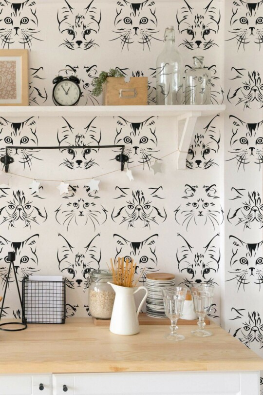 Cat Wallpaper with detailed black cat faces on a soft white background, styled in a cozy kitchen featuring open shelving, glass jars, and natural wood counters. The playful feline pattern adds a charming, whimsical accent to the space.