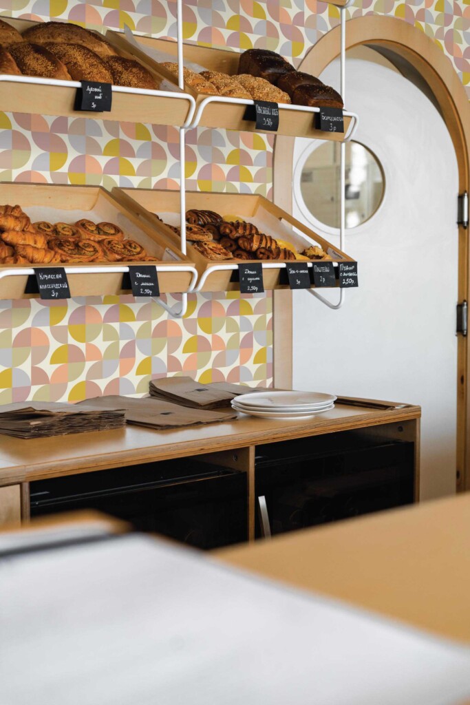 Minimalist bakery counter with wooden shelving and Bakery Retro Colorful wallpaper in the background. The curved geometric shapes bring retro charm to the space, creating a playful yet organized display setting.