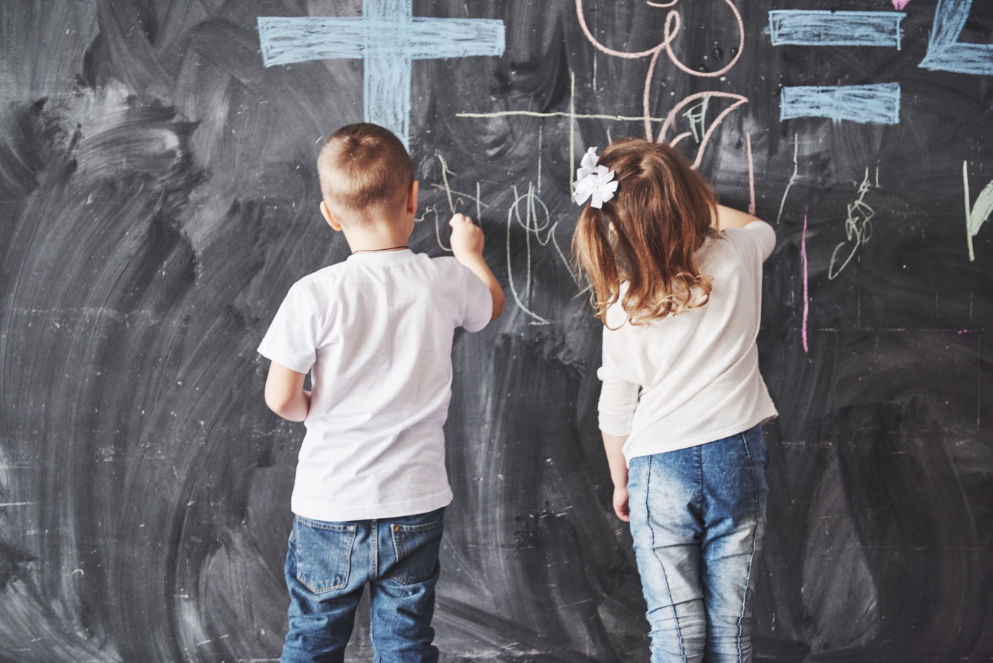 boy and girl drawing on chalkboard wall